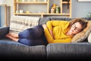 Frau liegt mit Bauchschmerzen auf Sofa Frau liegt mit Bauchschmerzen auf Sofa